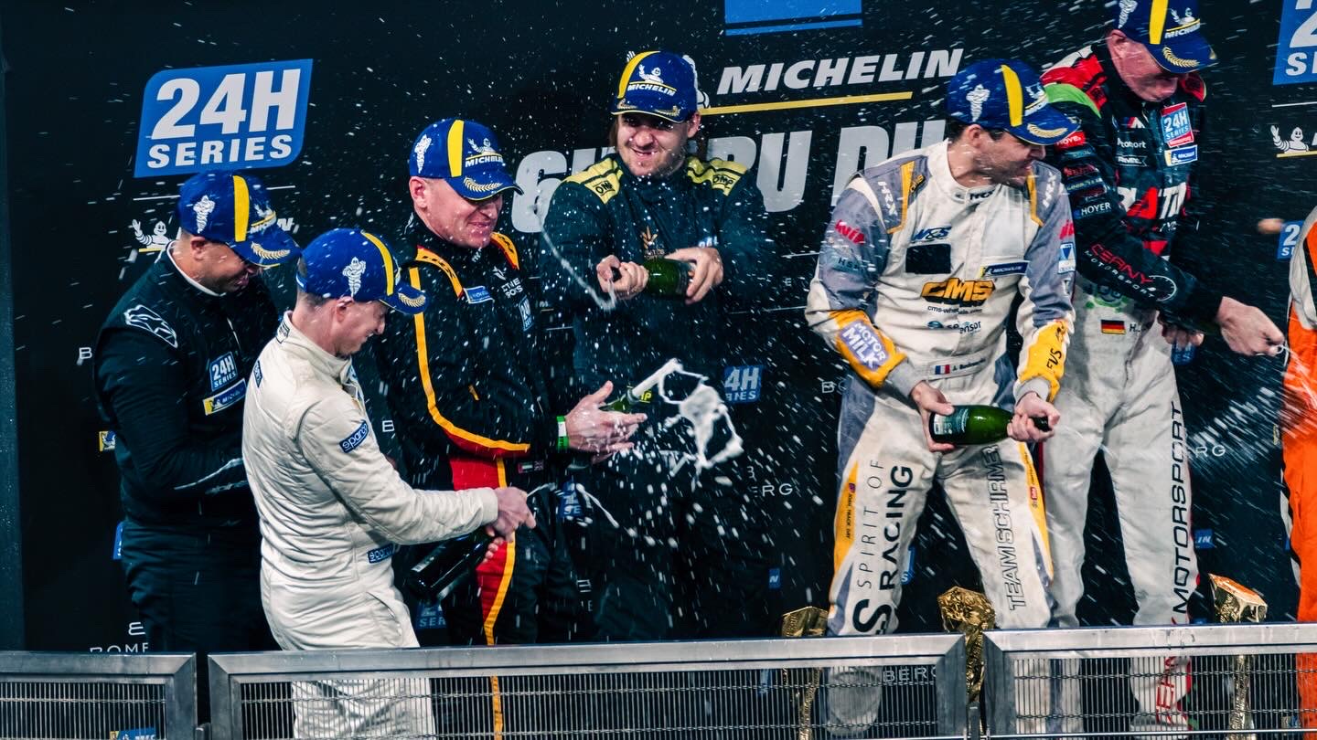 Will Powell celebrating on the podium with champagne